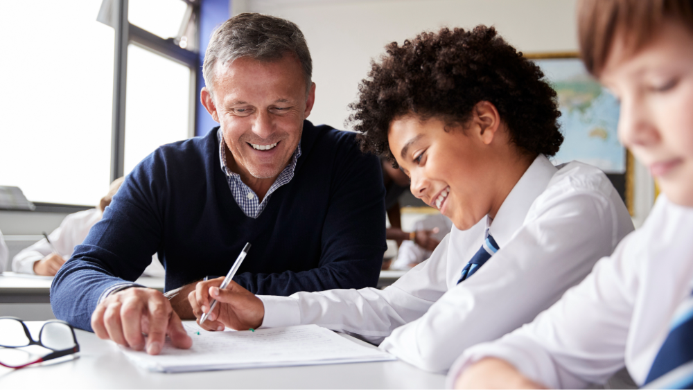 A secondary school teacher and student work together on a problem in the students workbook