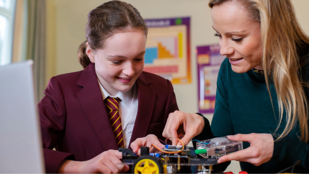 A secondary student and teacher working on a STEM project together in a classroom.