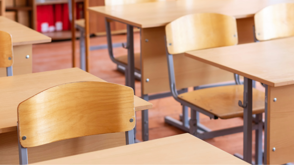 Multiple wooden school desks in a classroom