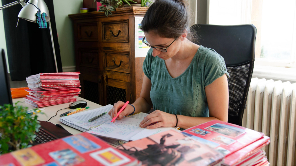 Teacher sitting at her desk marking school books.