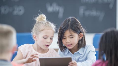 Two pupils use an ipad in a classroom